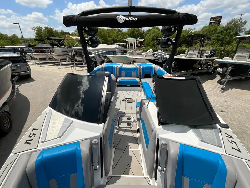 Slide: The Image of The image shows a 2022 Malibu 23LVS boat with blue and gray seating and a black wakeboard tower. - 33
