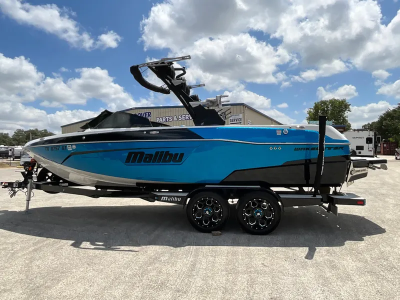 Slide: The Image of A blue and black 2022 Malibu 23LVS boat on a trailer under a cloudy sky. - 3