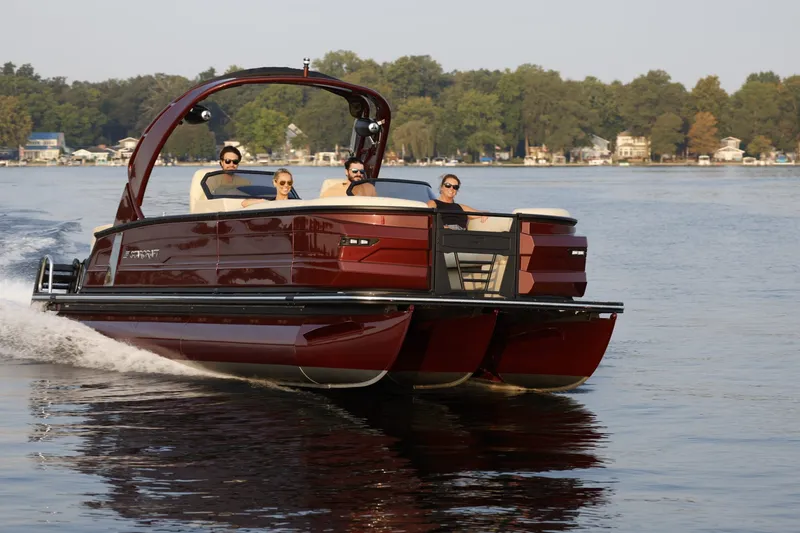 The Image of A sleek 2027 Starcraft pontoon boat glides on a calm lake with four people on board. - 1
