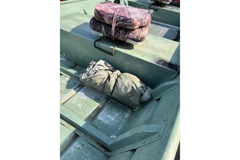 Slide: The Image of Green 1999 Jon Boat 1436 interior with camo cushions and gear bag. - 10