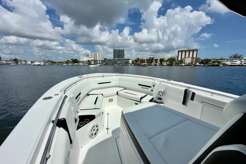 Slide: The Image of 2021 Blackfin 332 CC boat on calm water with city skyline and cloudy sky. - 25