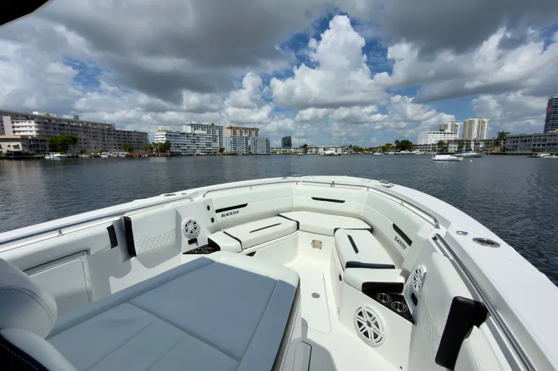 Slide: The Image of 2021 Blackfin 332 CC boat interior with luxurious seating, docked near urban waterfront. - 26