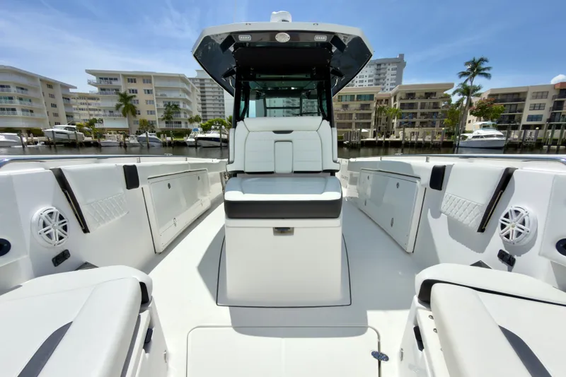 Slide: The Image of 2021 Blackfin 332 CC boat interior with modern seating and storage, docked near waterfront buildings. - 16