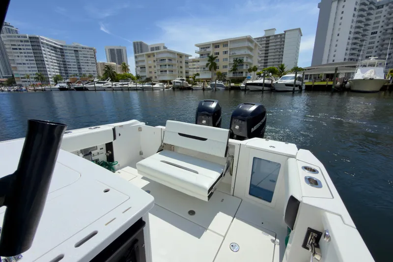 Slide: The Image of 2021 Blackfin 332 CC boat docked in a marina with cityscape background. - 13