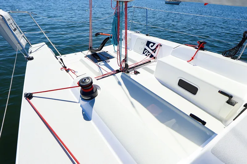 Slide: The Image of 2023 J Boats J/99 sailboat deck with winch and rigging on calm water. - 23
