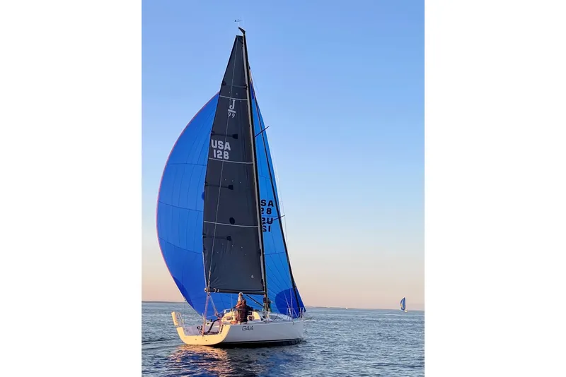 Slide: The Image of 2023 J Boats J/99 sailing with blue spinnaker on calm water at sunset. - 11