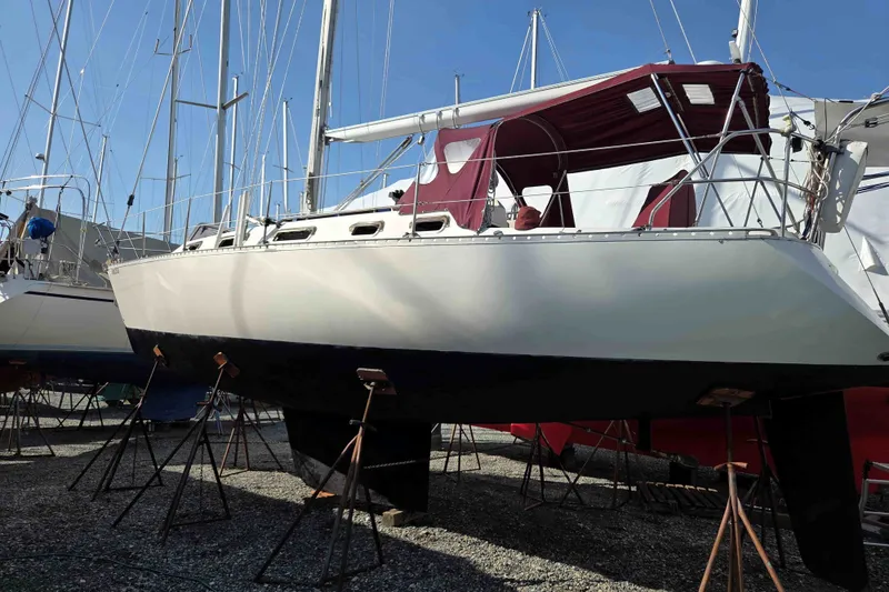 Slide: The Image of 1990 Canadian Sailcraft 34 sailboat on stands, with maroon canopy, in a boatyard. - 23