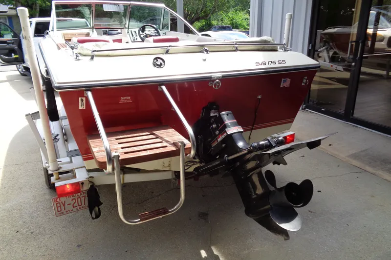 Slide: The Image of 1989 Stingray 172 SC boat with outboard motor and red hull, parked on trailer. - 3