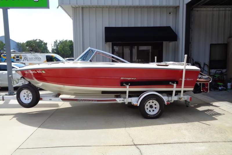 Slide: The Image of 1989 Stingray 172 SC boat in red on a trailer, parked outside a building. - 2