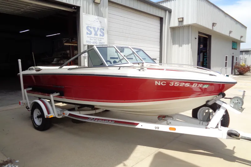 Slide: The Image of 1989 Stingray 172 SC boat on trailer, red and white, parked outside a garage. - 6