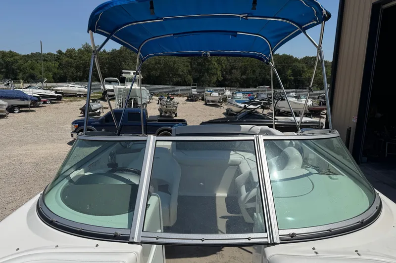 Slide: The Image of 2009 Rinker 248 Captiva Deckboat with blue canopy in a boatyard. - 5