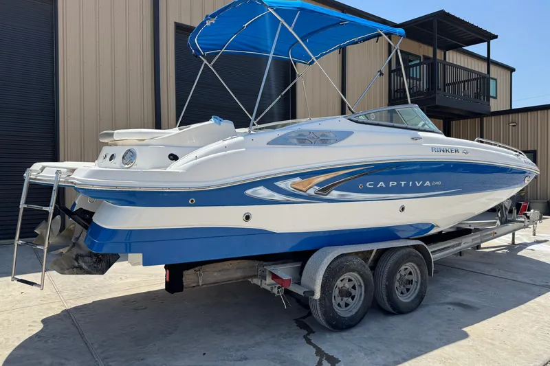 Slide: The Image of 2009 Rinker 248 Captiva Deckboat on trailer, blue and white, with canopy. - 17