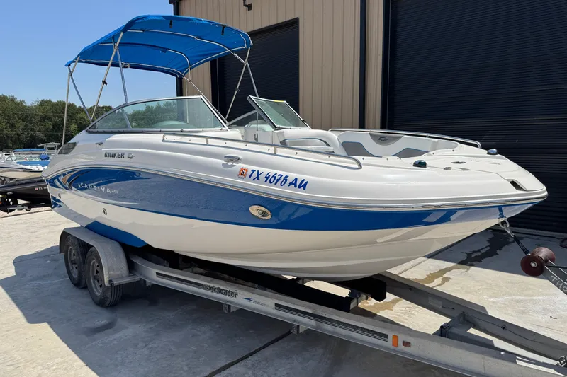 Slide: The Image of 2009 Rinker 248 Captiva Deckboat on trailer with blue canopy, parked outdoors. - 2