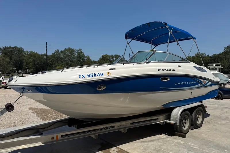 Slide: The Image of 2009 Rinker 248 Captiva Deckboat on trailer with blue canopy, parked outdoors. - 4