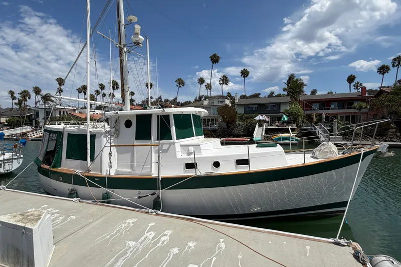 The Image of 1974 Willard Vega Voyager boat docked in a marina with palm trees and houses in the background. - 0