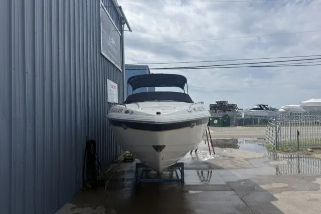 Slide: The Image of 2003 Chaparral 265 SSi boat docked beside a metal building under cloudy skies. - 2