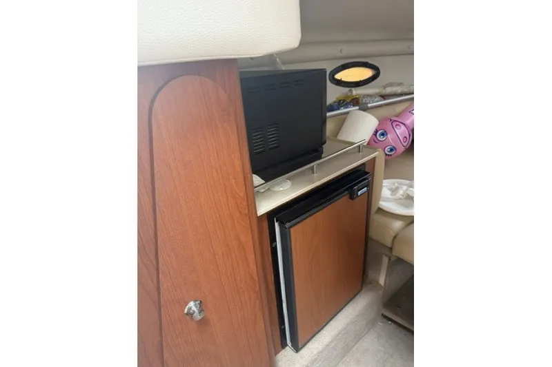 Slide: The Image of Interior of 2003 Chaparral 265 SSi boat with wooden cabinetry and mini fridge. - 7