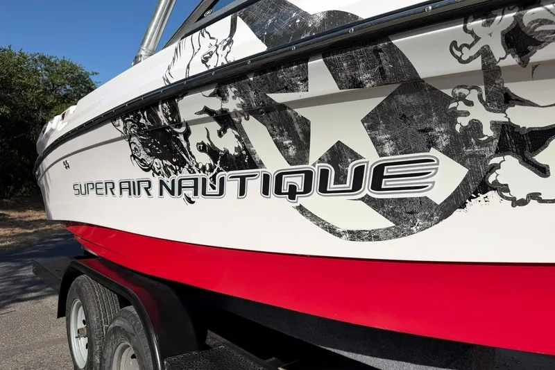 Slide: The Image of 2008 Correct Craft Super Air Nautique 210 boat with bold graphics on a trailer. - 47