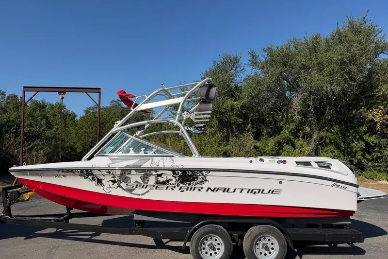 Slide: The Image of 2008 Correct Craft Super Air Nautique 210 boat on trailer, red and white design, outdoors. - 13