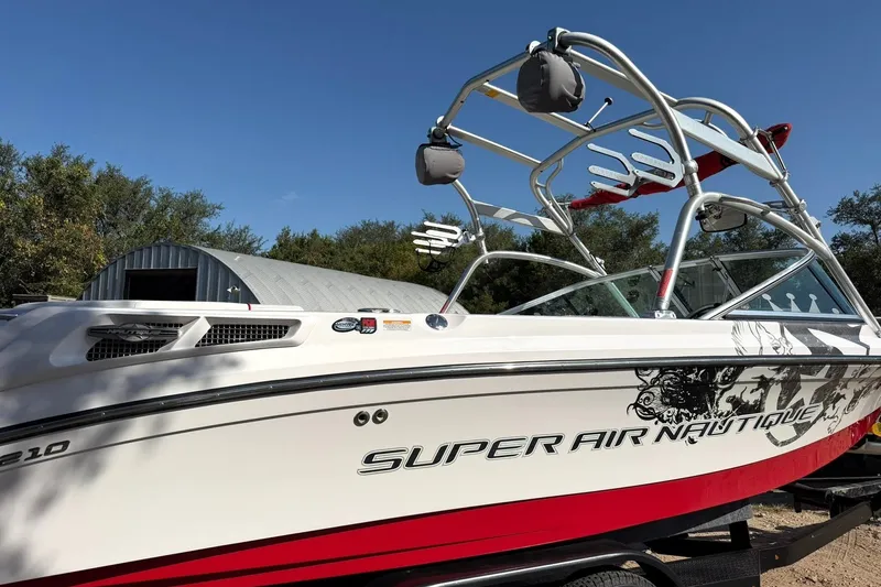 Slide: The Image of 2008 Correct Craft Super Air Nautique 210 boat with wakeboard tower, parked outdoors. - 11