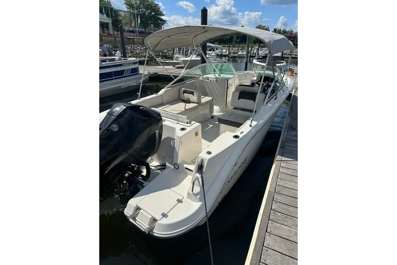 Slide: The Image of 2024 Sailfish 226 DC boat docked, featuring a spacious interior and outboard motor. - 11