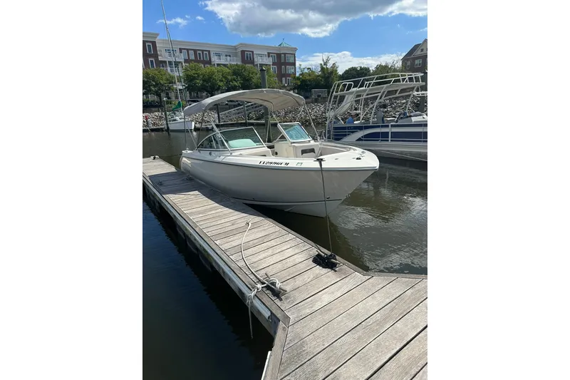Slide: The Image of 2024 Sailfish 226 DC boat docked at marina under clear blue sky. - 3