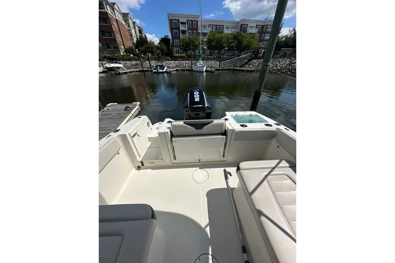 Slide: The Image of 2024 Sailfish 226 DC boat interior at a marina, showcasing seating and outboard motor. - 6