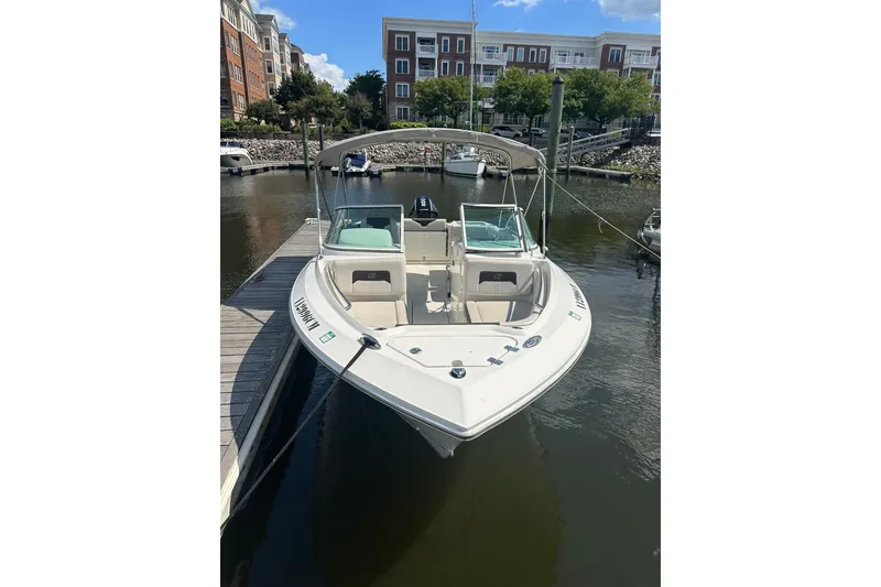 Slide: The Image of 2024 Sailfish 226 DC boat docked in a marina, featuring sleek design and spacious seating. - 2