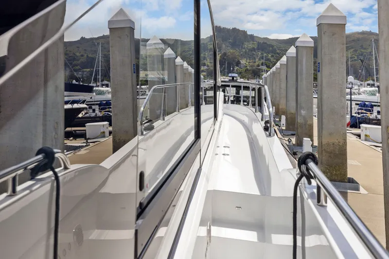 Slide: The Image of Ein modernes Boot mit glänzender Oberfläche liegt an einem Dock, umgeben von anderen Booten und Säulen. - 16