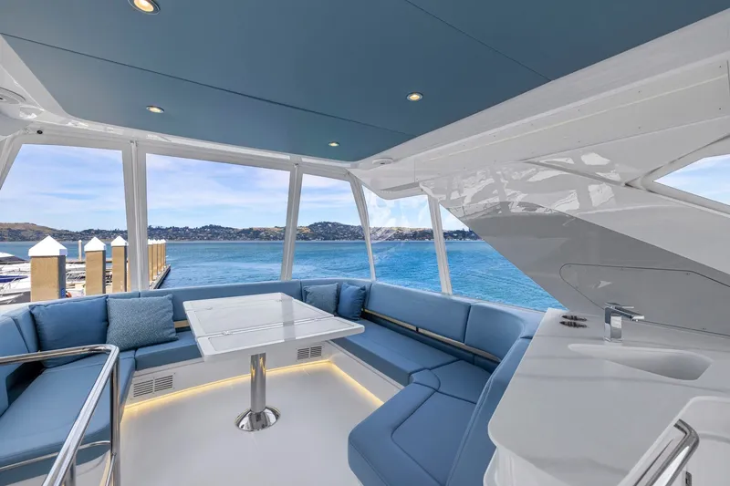 Slide: The Image of Das Bild zeigt den eleganten Innenraum einer Cruisers Yachts 57 Fly mit blauen Polstern und einem Tisch. - 33