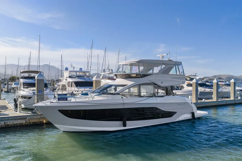 The Image of Die Cruisers Yachts 57 Fly von 2026 liegt im Hafen. Sie hat ein modernes Design mit großen Fenstern. - 0