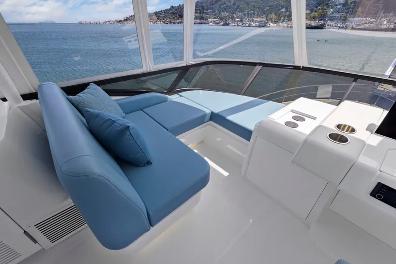 Slide: The Image of Das Bild zeigt das Cockpit einer Cruisers Yachts 57 Fly von 2026 mit blauen Polstern und Blick aufs Wasser. - 26