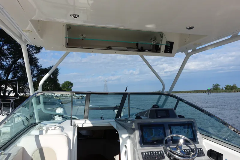 Slide: The Image of 2017 Robalo R305 Walkaround boat helm with dual displays, steering wheel, and open water view. - 26