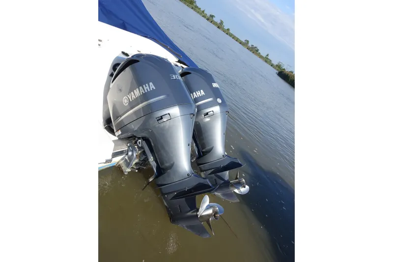 Slide: The Image of Twin Yamaha outboard engines on a 2017 Robalo R305 Walkaround boat, near a calm riverbank. - 15