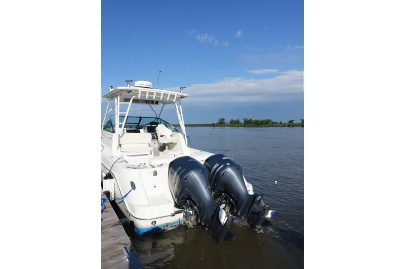 Slide: The Image of 2017 Robalo R305 Walkaround boat with dual Yamaha engines docked on calm water. - 14