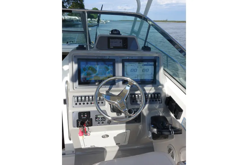 Slide: The Image of 2017 Robalo R305 Walkaround boat dashboard with dual screens and steering wheel. - 18