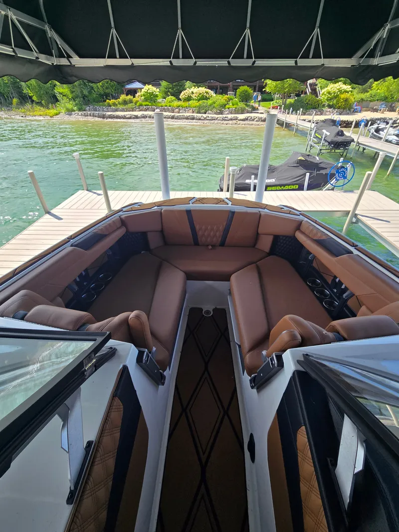 Slide: The Image of The image shows the interior of a 2024 Malibu M242 boat with brown seating and a dock in the background. - 4