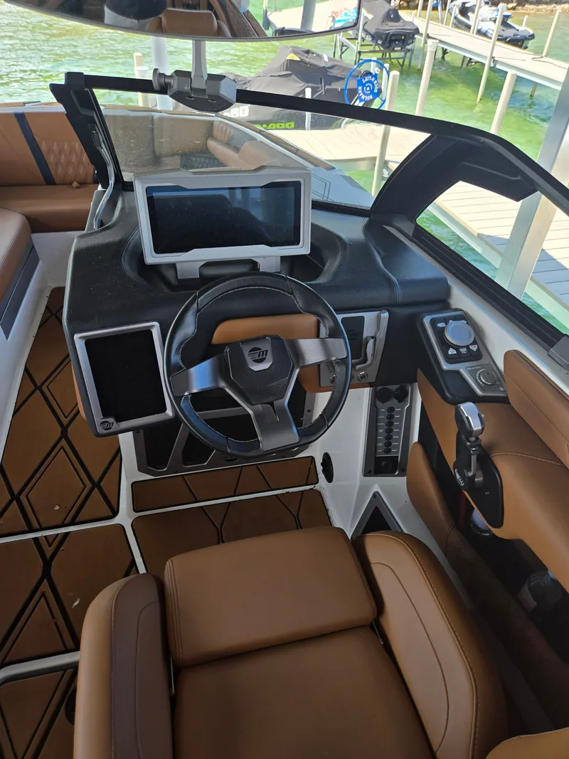 Slide: The Image of The image shows the cockpit of a 2024 Malibu M242 boat with modern instruments and brown seating. - 3