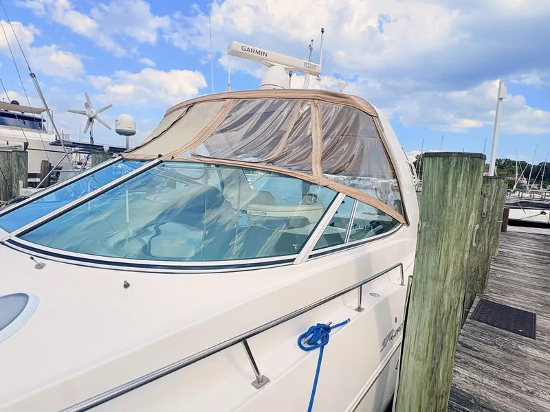Slide: The Image of A 2007 Cruisers 37O Express docked, featuring a beige canopy and clear windows. - 3