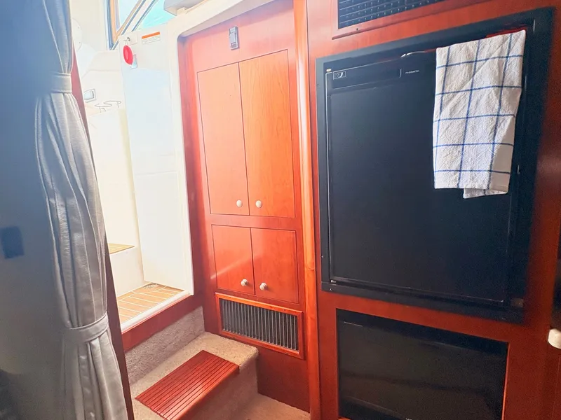 Slide: The Image of Interior of a 2007 Cruisers 37O Express with wooden cabinets and a black refrigerator. - 32