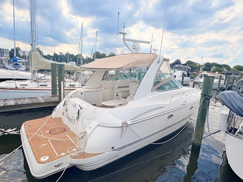 The Image of A white 2007 Cruisers 37O Express docked. It features a beige canopy and spacious cockpit. - 0