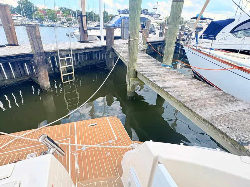 Slide: The Image of A boat is docked in a harbor next to a wooden pier. Other boats are visible in the background. - 34
