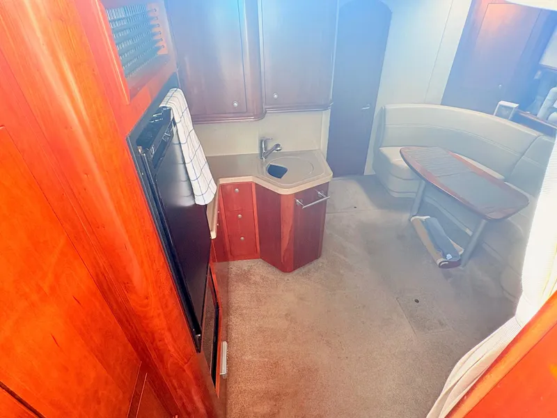 Slide: The Image of Interior of a 2007 Cruisers 37O Express with wood cabinetry, a small kitchenette, and seating area. - 19