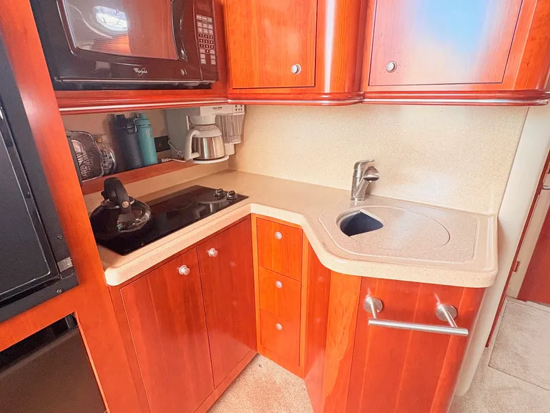 Slide: The Image of The 2007 Cruisers 37O Express kitchen features wooden cabinets, a cooktop, and a sink. - 21