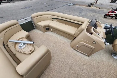 Slide: The Image of 2018 Bennington SSX21 boat interior with beige seating and helm, docked outdoors. - 10