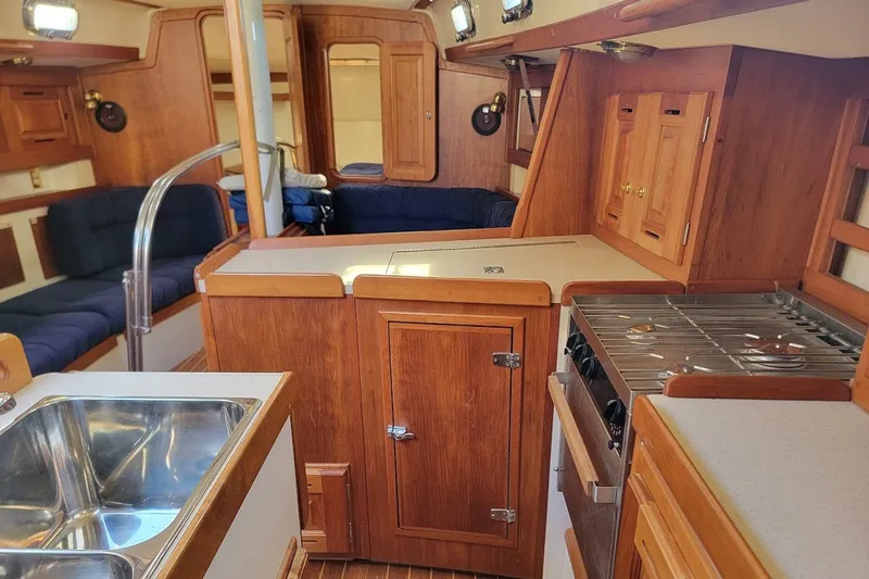 Slide: The Image of Interior of 2002 Tartan 3700 sailboat with wooden cabinetry and kitchen amenities. - 7