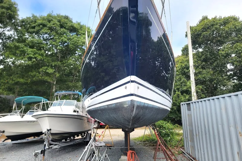 Slide: The Image of Tartan 3700 sailboat from 2002 on dry dock, surrounded by trees and other boats. - 33