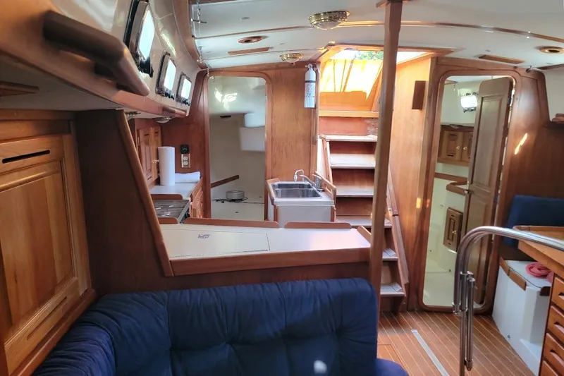 Slide: The Image of Interior of 2002 Tartan 3700 sailboat with wooden cabinetry and blue seating. - 15