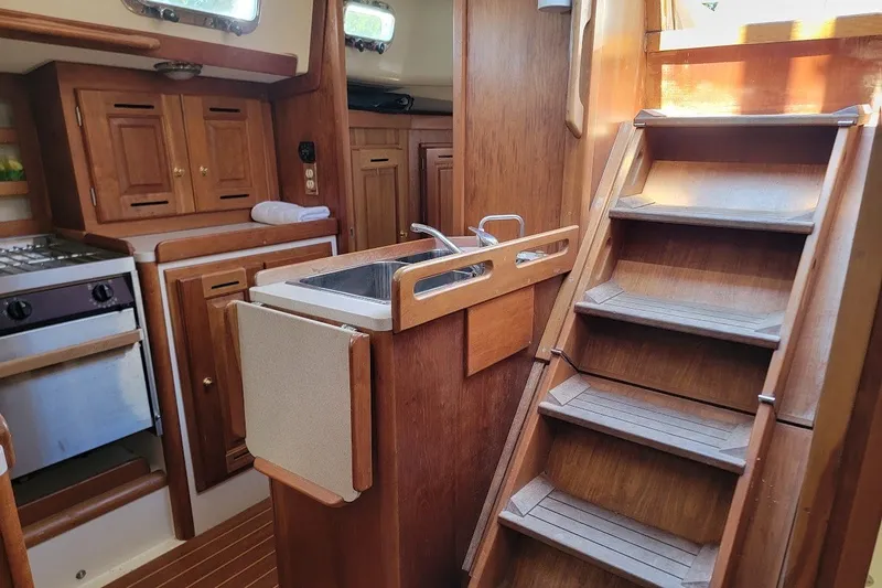 Slide: The Image of Interior of a 2002 Tartan 3700 sailboat featuring a compact kitchen and wooden stairs. - 10