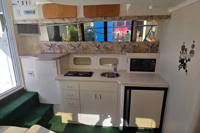 Slide: The Image of 1995 Mainship 31 Sedan Bridge interior kitchen with stove, sink, microwave, and cabinets. - 19